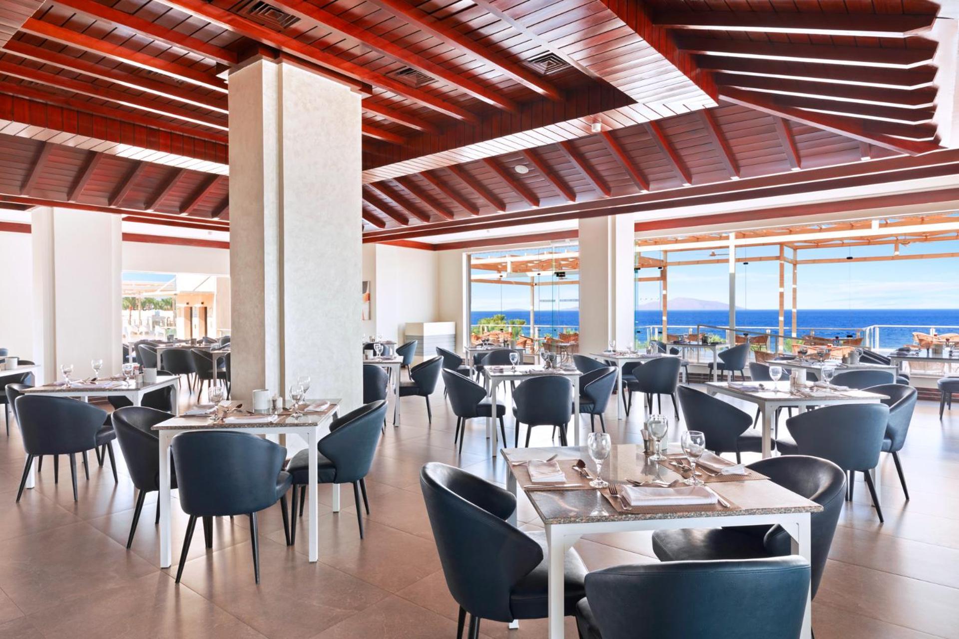 Pickalbatros Royal Grand Sharm - Adults Friendly 16 Years Plus Εξωτερικό φωτογραφία The photo shows a modern restaurant interior with a spacious and well-lit design. There are several tables set for dining, featuring white tablecloths and elegant dinnerware. The chairs are sleek and dark, contrasting with the bright surroundings. La