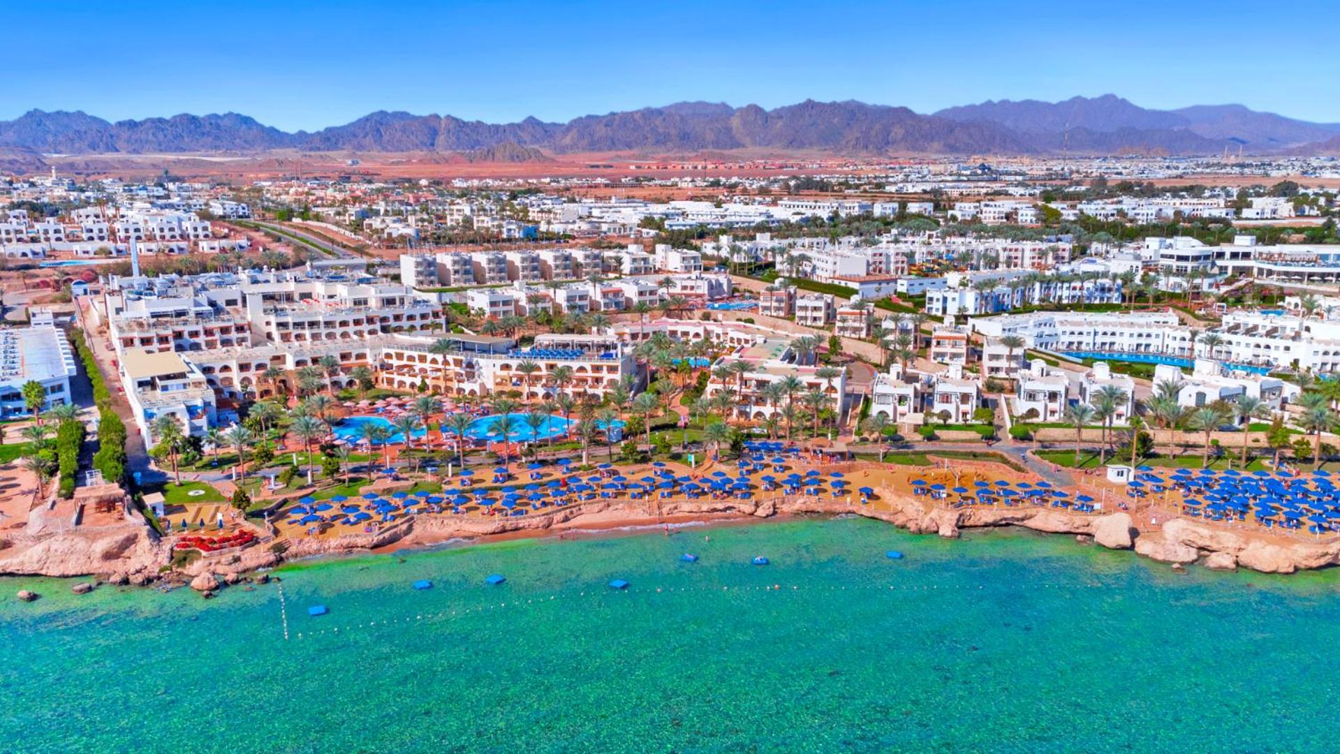 Pickalbatros Royal Grand Sharm - Adults Friendly 16 Years Plus Εξωτερικό φωτογραφία The photo shows an aerial view of a resort located by the coast. There are several swimming pools surrounded by sun loungers and umbrellas, as well as a beach area with clear turquoise water. In the background, there are multiple buildings of the res